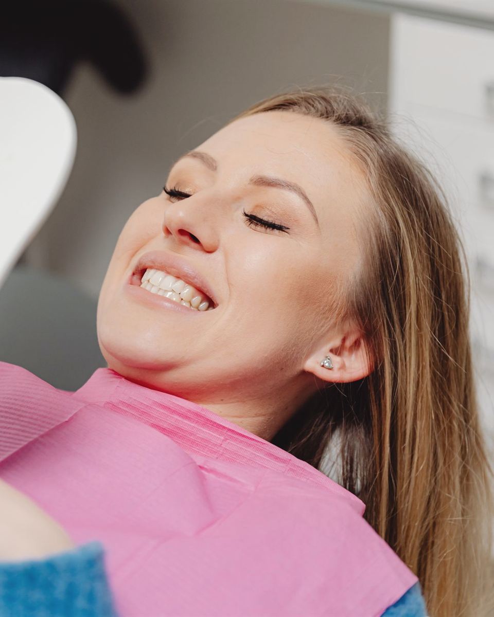 Paciente sonriendo mientras mira su sonrisa en un espejo, en el sillón dental