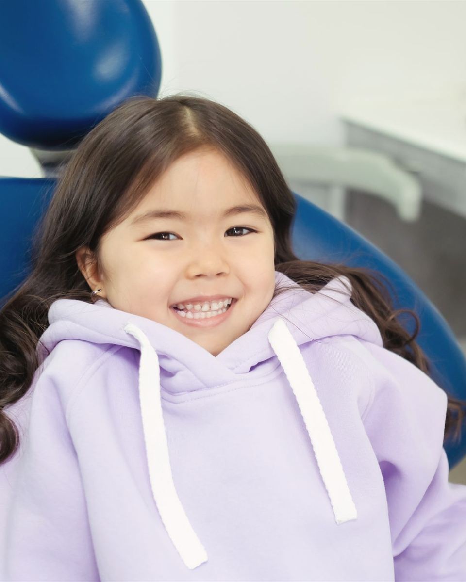 Niña sonriendo sentada en el sillón dental