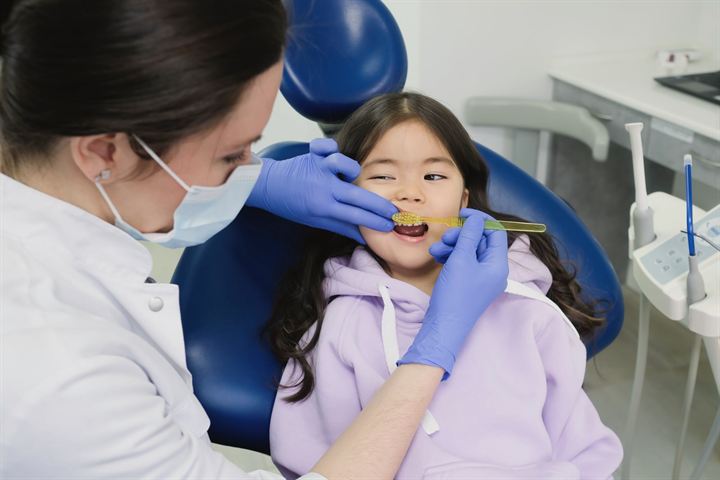 Dentista revisando a una niña que sonríe en el sillón